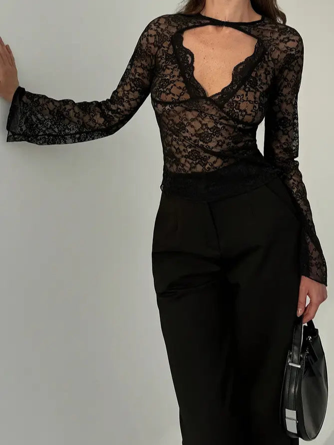 Woman wearing a black lace top and black pants against a white background